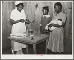 Nurse Shamburg demonstrates care of baby bottles to Mrs. Paralee Coleman and Marie. Mothers have to work in field and children are left at home to care for babies. Health clinic, Gee's Bend, Alabama