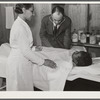 Project nurse Lillie Mae McCormick assists Dr. Thomas M. Adams as he takes Annie Maude Daniels' blood pressure on table in health clinic. Flint River Farms, Georgia