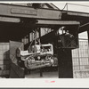 Shepard crane lifting tractor brought to FSA (Farm Security Administration) warehouse depot for repairs. Atlanta, Georgia