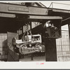 Shepard crane lifting tractor brought to FSA (Farm Security Administration) warehouse depot for repairs. Atlanta, Georgia