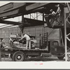 Hooking shepard crane to tractor preparatory to hoisting it off truck to repairs shop in FSA (Farm Security Administration) warehouse depot. Atlanta, Georgia