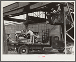 Hooking shepard crane to tractor preparatory to hoisting it off truck to repairs shop in FSA (Farm Security Administration) warehouse depot. Atlanta, Georgia