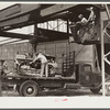 Hooking shepard crane to tractor preparatory to hoisting it off truck to repairs shop in FSA (Farm Security Administration) warehouse depot. Atlanta, Georgia