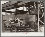 Hooking shepard crane to tractor preparatory to hoisting it off truck to repairs shop in FSA (Farm Security Administration) warehouse depot. Atlanta, Georgia