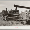 Loading repaired tractor from bank to truck ready to leave FSA (Farm Security Administration) warehouse depot in Atlanta, Georgia