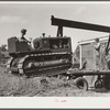 Loading repaired tractor from bank to truck ready to leave FSA (Farm Security Administration) warehouse depot in Atlanta, Georgia