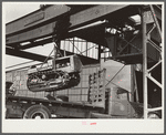 Tractor, transported by truck to FSA (Farm Security Administration) warehouse depot for repairs, being hoisted by Shepard crane to shop inside. Atlanta, Georgia