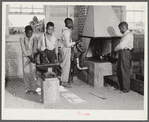 O.C. Cramer, Frederick West, J.W. West and another student sharpening plow point at forge in school shop. Flint River Farms, Georgia