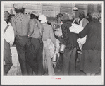 Black day laborers brought in truck from nearby towns, waiting to be paid off for cotton picking and buy supplies inside plantation store on Friday night. Marcella Plantation. Mississippi Delta. Mississippi