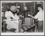 Black day laborers brought in truck from nearby towns, waiting to be paid off for cotton picking and buy supplies inside plantation store on Friday night. Marcella Plantation. Mississippi Delta. Mississippi