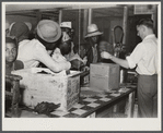Black day laborers brought in truck from nearby towns, waiting to be paid off for cotton picking and buy supplies inside plantation store on Friday night. Marcella Plantation. Mississippi Delta. Mississippi