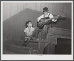Two Mexican children on steps of railway station where they live during the cotton picking season on Knowlton Plantation, Perthshire. This transient labor is contracted for and brought in trucks from Texas each season