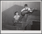 Two Mexican children on steps of railway station where they live during the cotton picking season on Knowlton Plantation, Perthshire. This transient labor is contracted for and brought in trucks from Texas each season