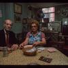 Man in red tie and woman in blue apron seated at table, Retired Owners and Workers