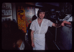 Restaurant worker in front of kitchen murals, Symposium Restaurant