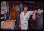 Restaurant worker in front of kitchen murals, Symposium Restaurant