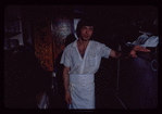 Restaurant worker in front of kitchen murals, Symposium Restaurant