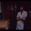 Restaurant worker in front of kitchen murals, Symposium Restaurant