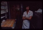 Restaurant worker in front of kitchen murals, Symposium Restaurant