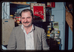 Man seated in front of Coca-Cola clock, Plaza de Athena I