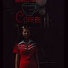 Waitress outdoors in front of "Worlds Finest Coffee" neon sign, Have a Donut Coffee Shop