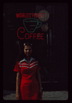 Waitress outdoors in front of "Worlds Finest Coffee" neon sign, Have a Donut Coffee Shop