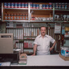 Grocer with white shirt behind counter, Grocer #2