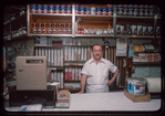 Grocer with white shirt behind counter, Grocer #2