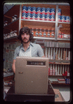 Grocer with grey shirt behind counter, Grocer #2
