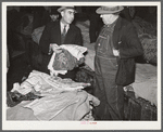 Farmers listening to Armenian bedspread, table linen, and shawl salesman in warehouse during tobacco auctions. Durham, North Carolina