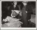 Farmers listening to Armenian bedspread, table linen, and shawl salesman in warehouse during tobacco auctions. Durham, North Carolina