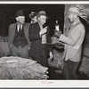 Farmers listening to sales talk of patent medicine vendor in warehouse during tobacco auctions. Durham, North Carolina