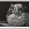 Unloading tobacco from trailer into baskets according to the grade the night before auction sale in warehouse. Durham, North Carolina