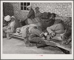 Farmers sleeping in [Black] camp room in warehouse. They often must remain overnight or several days before their tobacco is auctioned. Several of them are using an old tobacco basket for a pillow. Durham, North Carolina