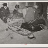 Farmers sleeping in [Black] camp room in warehouse. They often must remain overnight or several days before their tobacco is auctioned. One of them is using an old tobacco basket for a pillow. Durham, North Carolina