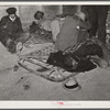 Farmers sleeping in [Black] camp room in warehouse. They often must remain overnight or several days before their tobacco is auctioned. One of them is using an old tobacco basket for a pillow. Durham, North Carolina