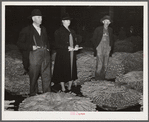 Farmer and his wife waiting for their tobacco to be sold at auction in warehouse. Durham, North Carolina