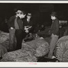 Salesman in tobacco warehouse selling shoes and boots to farmers during auction sale. Durham, North Carolina