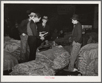 Salesman in tobacco warehouse selling shoes and boots to farmers during auction sale. Durham, North Carolina