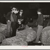 Salesman in tobacco warehouse selling shoes and boots to farmers during auction sale. Durham, North Carolina