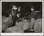 Salesman in tobacco warehouse selling shoes and boots to farmers during auction sale. Durham, North Carolina