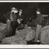 Salesman in tobacco warehouse selling shoes and boots to farmers during auction sale. Durham, North Carolina