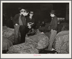 Salesman in tobacco warehouse selling shoes and boots to farmers during auction sale. Durham, North Carolina