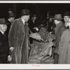 Warehouseman and auctioneer with buyers in background during tobacco auction sale. Durham, North Carolina