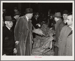 Warehouseman and auctioneer with buyers in background during tobacco auction sale. Durham, North Carolina