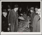 Warehouseman and auctioneer with buyers in background during tobacco auction sale. Durham, North Carolina