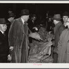 Warehouseman and auctioneer with buyers in background during tobacco auction sale. Durham, North Carolina