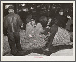 Farmers and friends waiting around in tobacco warehouse during auction sale. Durham, North Carolina