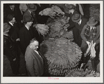 Auctioneer, buyers, and farmers during tobacco auction sale. Warehouse, Durham, North Carolina