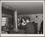 High school students getting warm and drying mittens by stove in ski hut